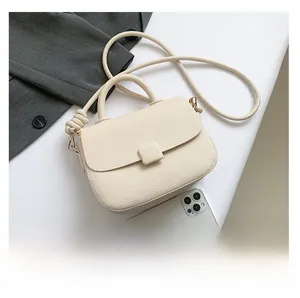 Detail of off-white lychee grain crossbody bag with top handle and knot strap detail
