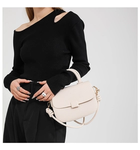 Detail view of cream leather crossbody bag featuring unique knotted shoulder strap