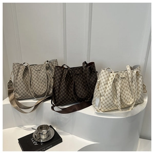 Dettaglio di borse tote con motivi geometrici in grigio, marrone e crema su podio