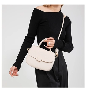 Chic cream leather handbag with thick knotted shoulder strap worn by a model in black