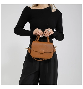 Detail shot of brown lychee grain leather mini bag with knotted shoulder strap and top handle