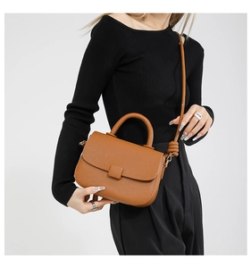 Close-up of caramel leather crossbody bag with lychee texture and unique knot strap detail