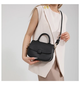 Detail of black lychee grain leather saddle bag with square buckle and adjustable strap