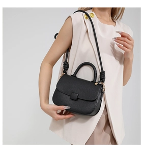 Close-up of black lychee grain crossbody bag with creative woven knot shoulder strap