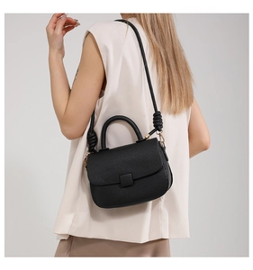 Detail of black lychee grain leather crossbody bag with knot shoulder strap details