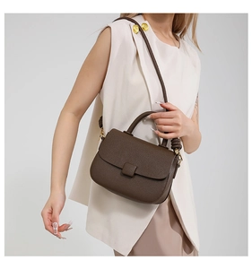Detail of dark brown lychee grain leather crossbody bag with spiral strap accent
