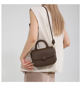 Detail view of dark brown pebbled leather crossbody bag with top handle and knotted strap