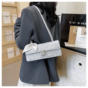 Détail du sac sous l'aisselle en velours argenté avec boucle cristal et nœud blanc