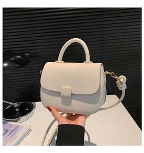 Detail of white lychee leather handbag with knot strap and gold-tone hardware