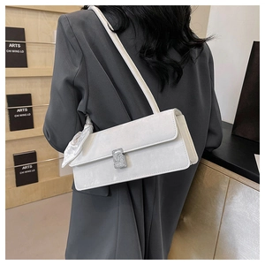 Détail d'un sac à bandoulière en cuir blanc avec boucle en cristal et foulard en soie
