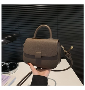 Close-up of brown litchi pattern leather texture and saddle shape handle design