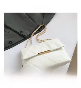 Close-up of quilted white leather texture and gold metal clasp on a chain bag