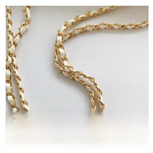 Detail of elegant gold metal chain woven with white leather strap for shoulder bag