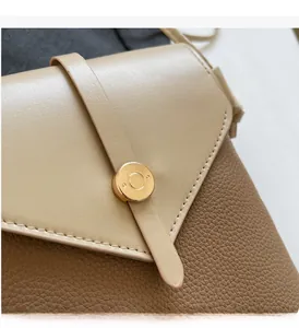 Close-up of contrast color crossbody bag with pebble grain leather and gold metal lock