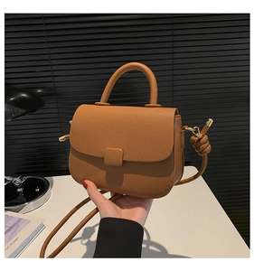 Brown litchi grain leather saddle bag with unique knotted adjustable strap detail
