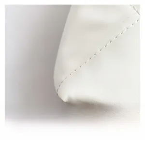 Detailed macro view of white quilted leather texture with premium stitching on handbag