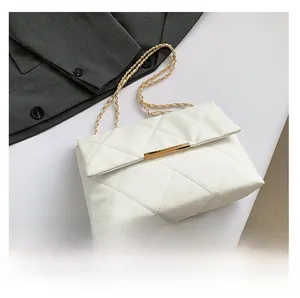 Detailed top view of white quilted crossbody bag with gold chain strap on blazer