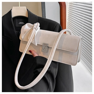 Détail d'un sac bandoulière en daim blanc cassé avec boucle S et foulard décoratif