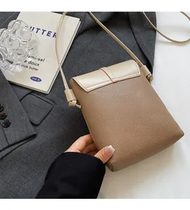 Close-up of beige lychee texture leather small square crossbody bag on a grey blazer