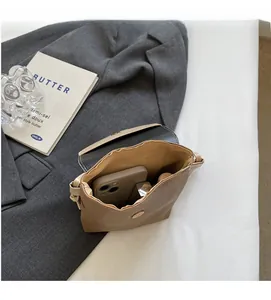 Detail showing internal compartment of a brown textured crossbody bag with daily essentials