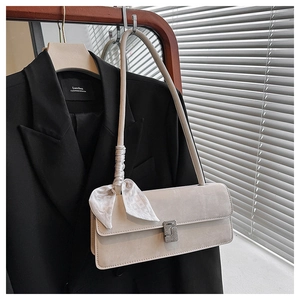 Détail du sac beige avec nœud en foulard de soie et boucle en diamant brillant