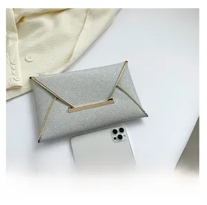 Detailweergave van zilveren glitter enveloptas met goudrand en vergelijking met telefoon