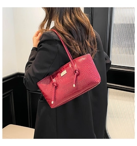 Close-up of wine red crocodile embossed tote bag with unique knot detail and metal logo