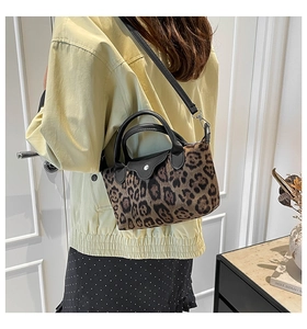 Macro detail of leopard print fabric texture and black leather handle on handbag