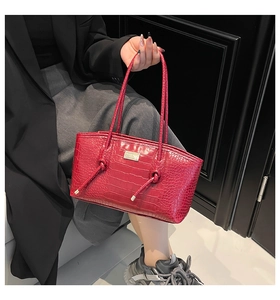 Detail of red crocodile texture tote bag with metallic logo and elegant carry handles