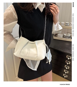 Detail of a minimalist beige pleated shoulder bag with silver chain strap on a model