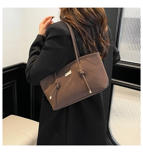 Detailed close-up of brown quilted faux leather tote bag with elegant tassel accent