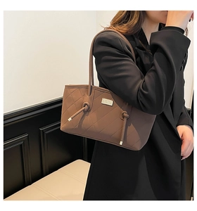 Detail showing brown quilted tote bag texture with elegant decorative knots and metal logo