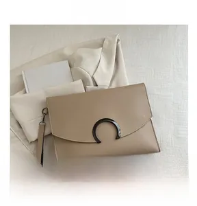 Minimalist envelope clutch detail showing textured leather and magnetic metal buckle