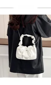 Détail du nœud blanc et de l'anse plissée sur ce sac à bandoulière élégant avec chaîne