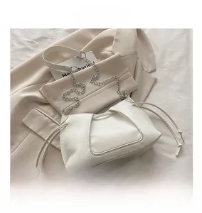 Detail of cream leather shoulder bag featuring drawstring closure and silver chain strap