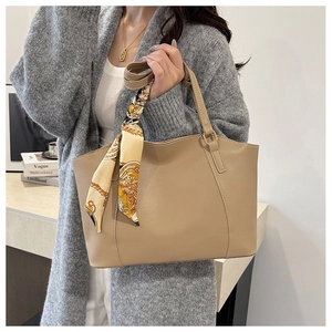 Detailed shot of khaki leather tote bag with printed silk scarf handle and golden hardware