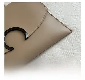 Macro shot of precise stitching and black metal ring hardware on the brown leather clutch