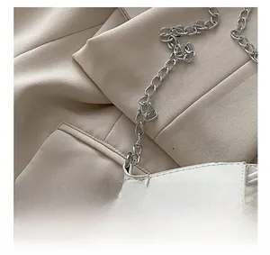 Close-up of white leather bag featuring a chunky silver chain strap and premium stitching