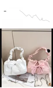 Detail of bow-knot handbags in white and pink with pleated handles and chain straps