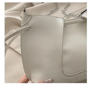 Detail showing white leather shoulder bag with drawstring closure and metal chain strap