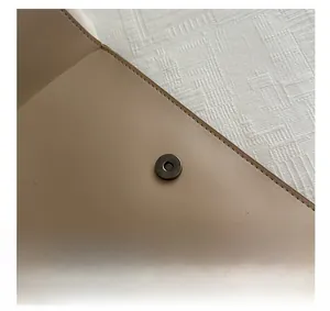 Macro shot of light brown leather envelope bag featuring a secure round magnetic closure