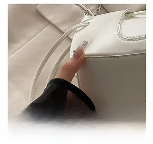 Detail of white leather shoulder bag featuring precision stitching and metal chain strap