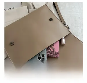 Flat lay view of khaki envelope clutch bag showing storage capacity for daily essentials
