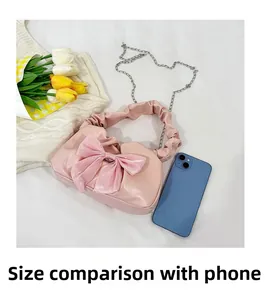 Sac à main rose avec nœud et poignée froncée à côté d'un téléphone pour comparer la taille