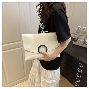 Detailed side view of white envelope crossbody bag with black C-shaped buckle detail