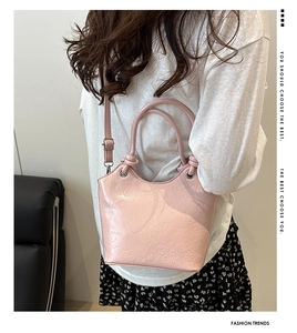 Detail of pink crossbody bag with embossed cartoon patterns and round handle