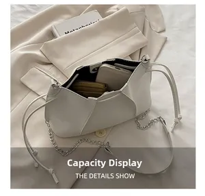 Detail view of large capacity white pleated bag with silver chain strap on white blazer
