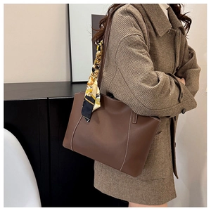Gros plan d'un sac cabas en cuir marron avec surpiqûres et foulard en soie décoratif