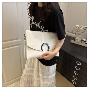 Detail shot of the white envelope bag featuring a bold black U-shaped metal lock buckle
