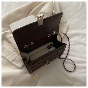 Detail of coffee brown quilted crossbody bag showing interior capacity and silver lock